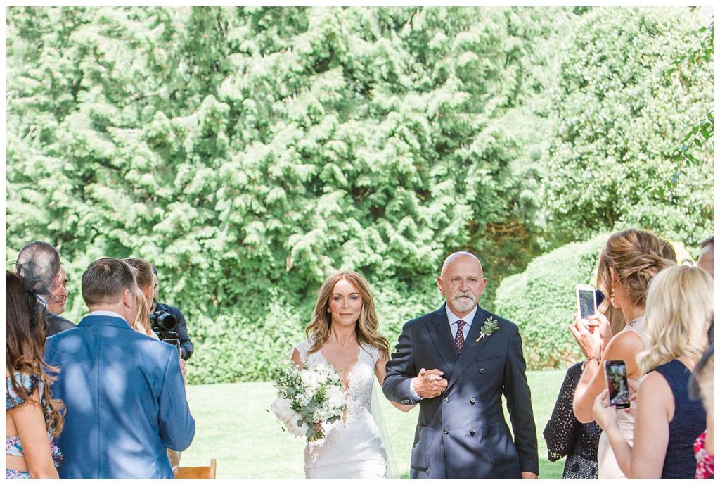 bride walking with father outdoor ceremony Barnsley house wedding photography