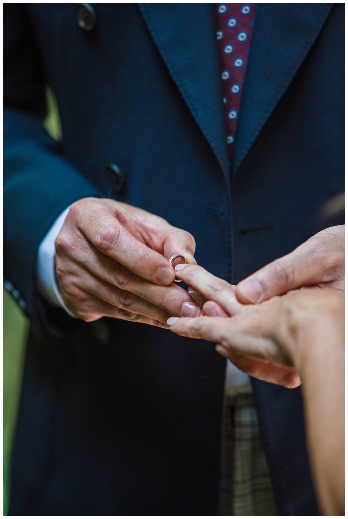 groom putting on wedding ring Barnsley House